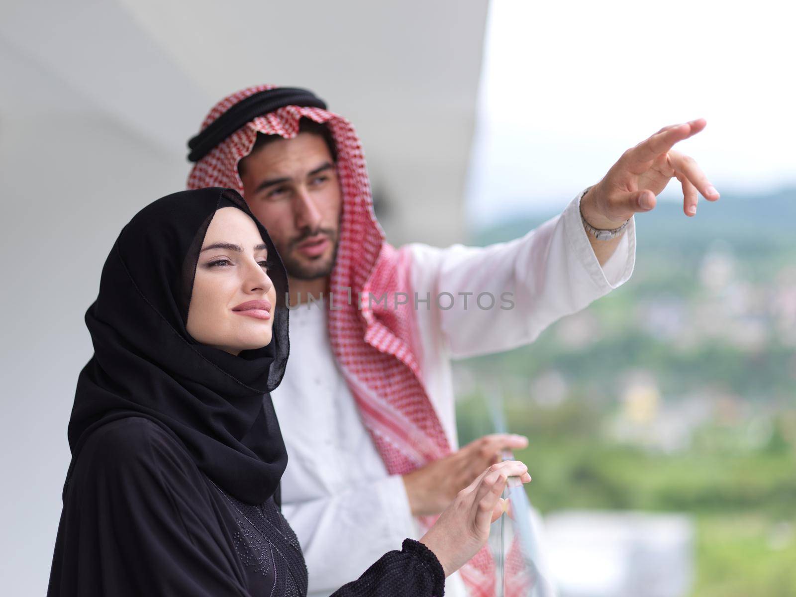 portrait of beautiful arabian couple standing on balcony by dotshock