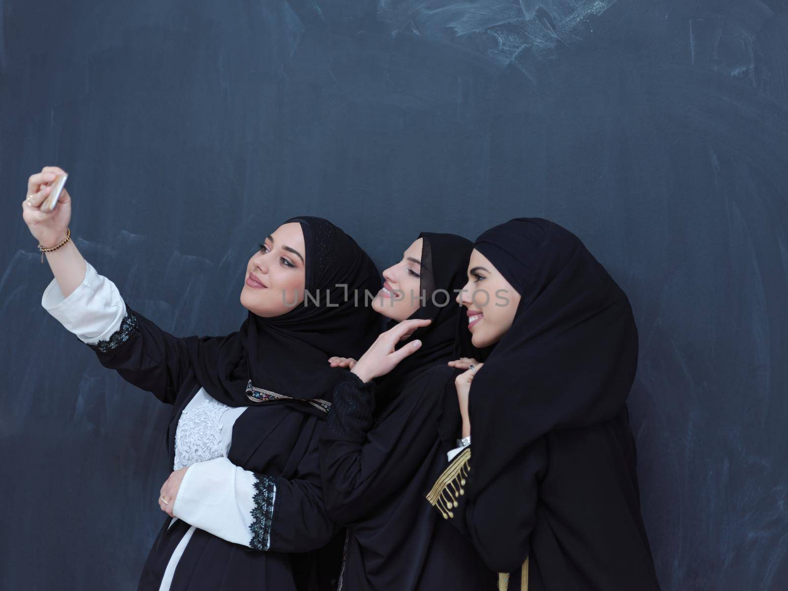 muslim women taking selfie picture in front of black chalkboard by dotshock