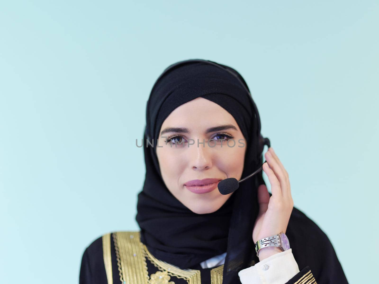 portrait of muslim female with hijab scarf customer representative business woman with phone headset helping and supporting online with customer in modern call centre isolated on cyan background