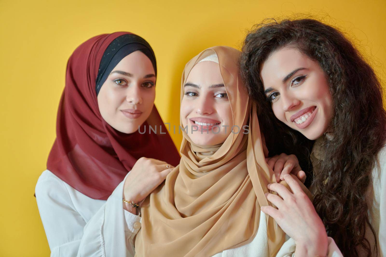 Young muslim women posing on yellow background. Happy and pretty girls two wearing hijab representing Ramadan concept