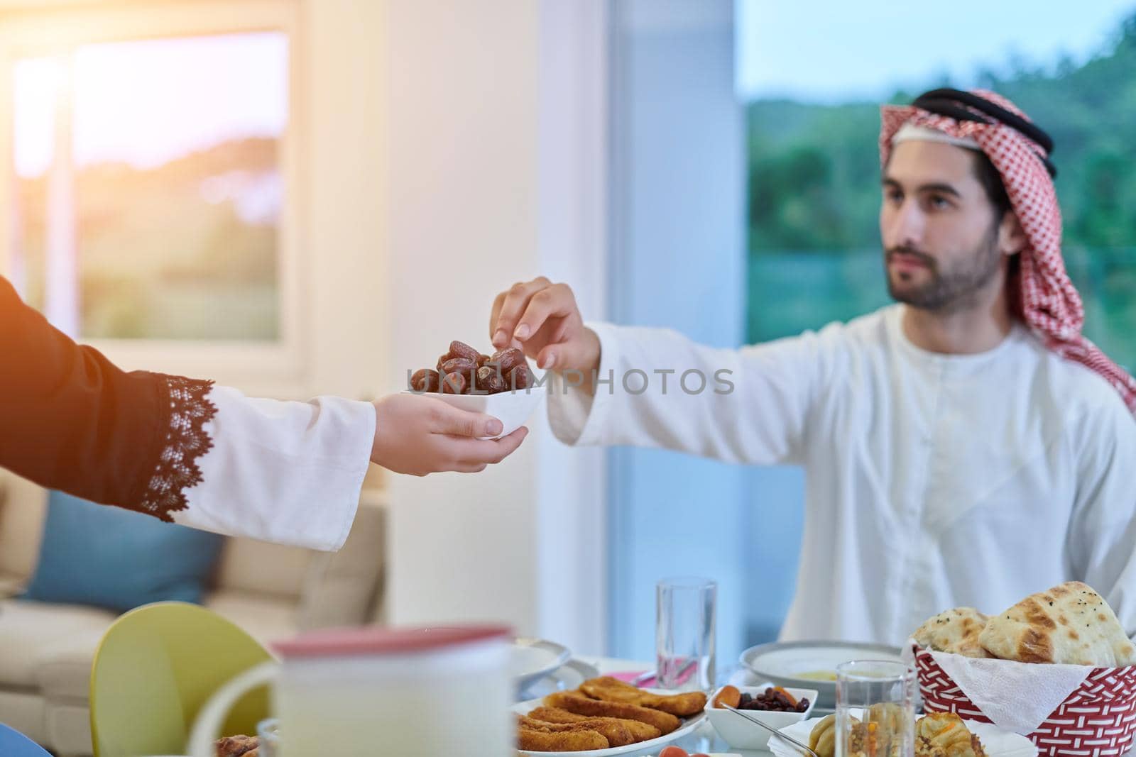 Muslim couple sharing dates for starting iftar. Arabian woman serving bowl with dates to man for breaking fast during Ramadan.