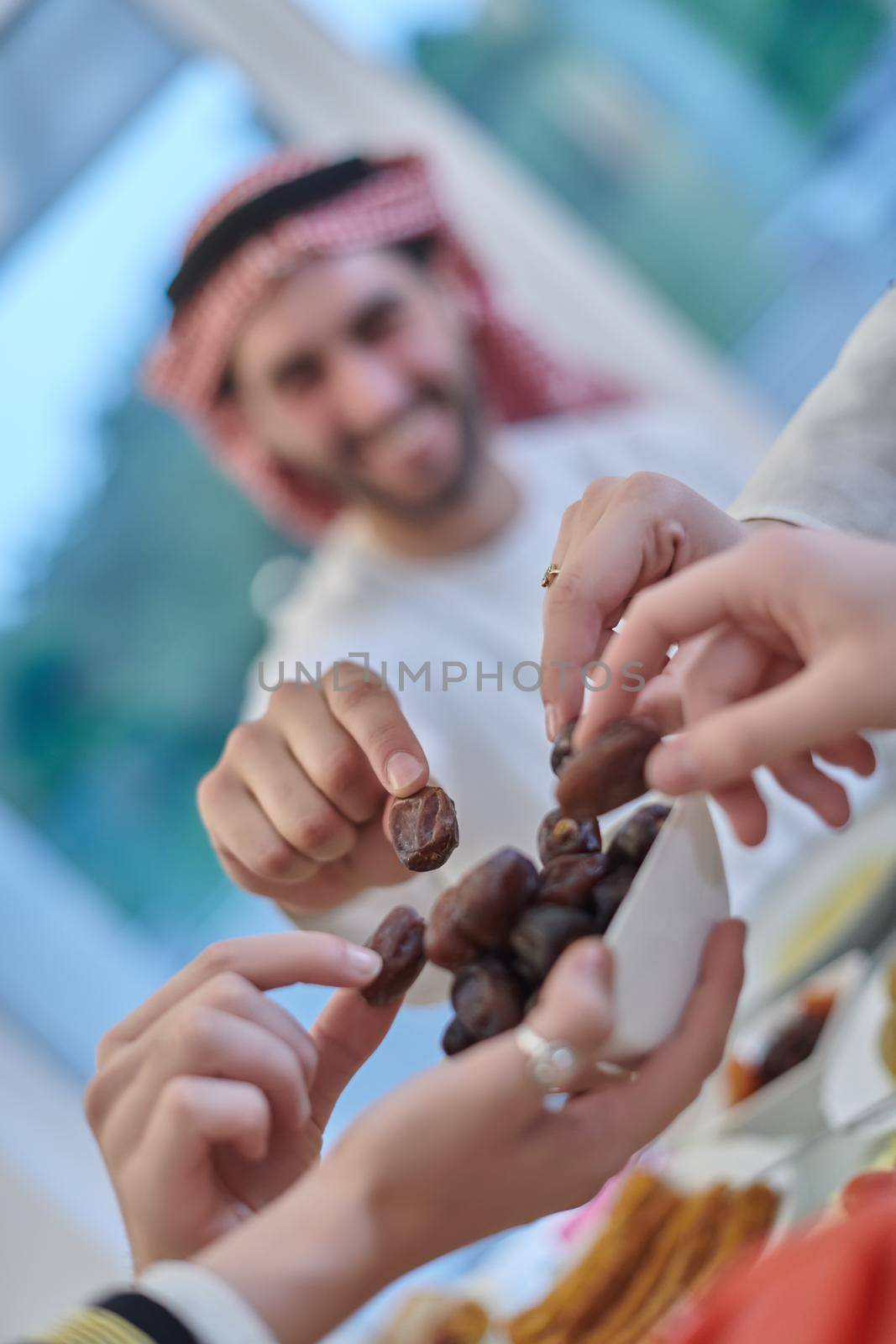 Muslim family having iftar together during Ramadan. Arabian people gathering for traditional dinner during fasting month. Dates sharing to break fasting