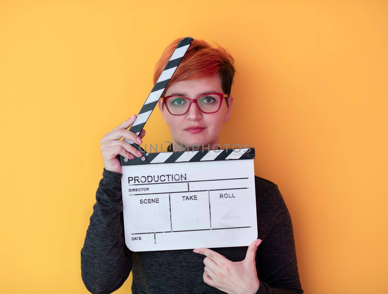redhead woman holding movie  clapper on yellow background by dotshock