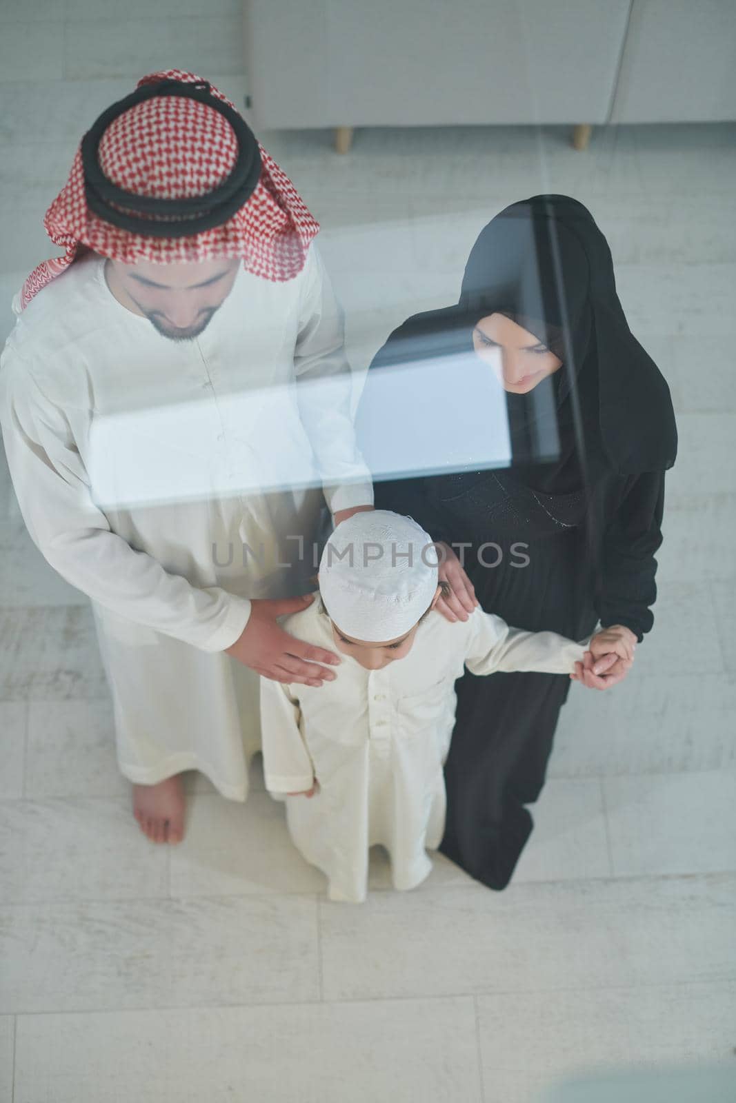 Top view of young arabian muslim family wearing traditional clothes at their modern house spending time together during Ramadan