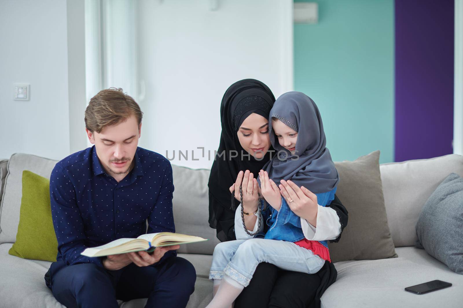 Young muslim family reading Quran during Ramadan by dotshock