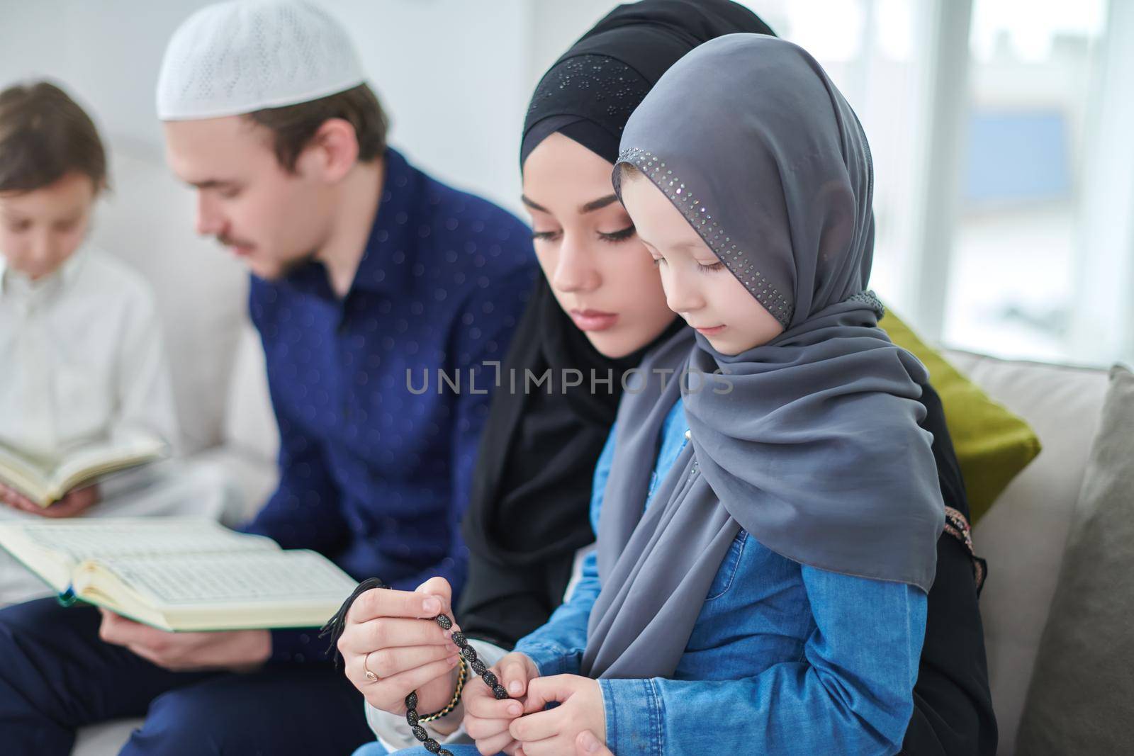 Young muslim family reading Quran during Ramadan by dotshock