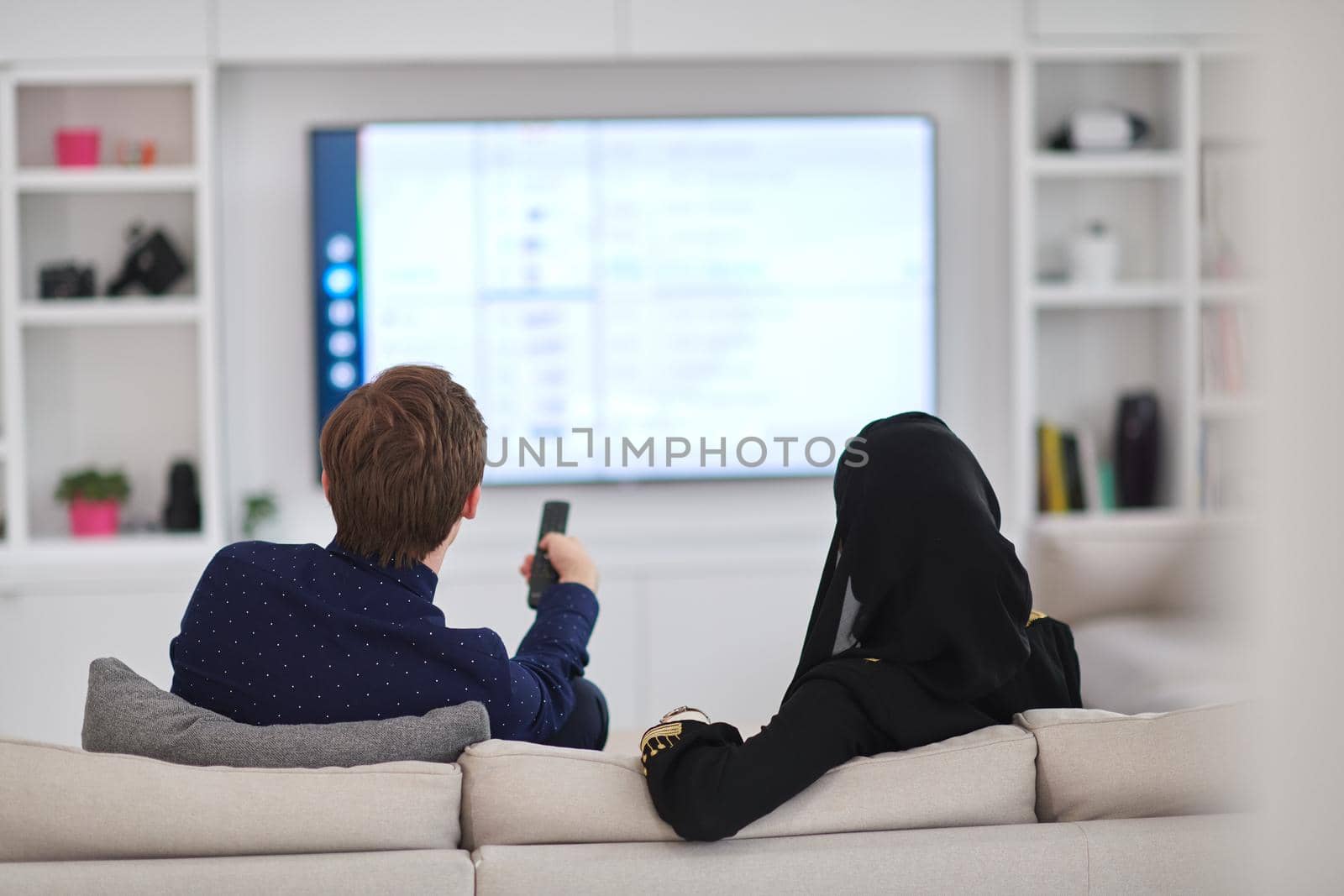 Young muslim couple enjoing time together at home during Ramadan. Happy arabic family watching TV