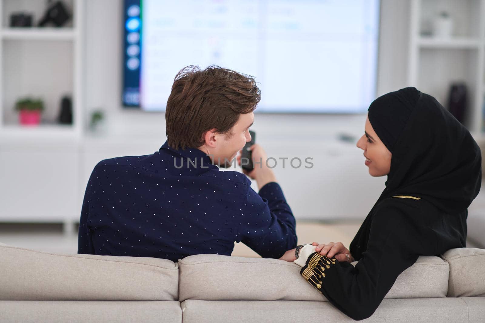 Young muslim couple enjoing time together at home during Ramadan. Happy arabic family watching TV