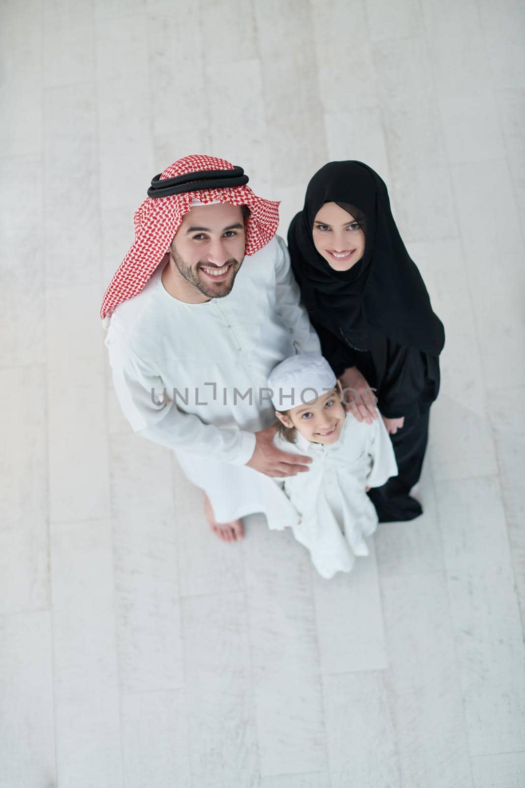 Top view of young arabian muslim family wearing traditional clothes at their modern house spending time together during Ramadan