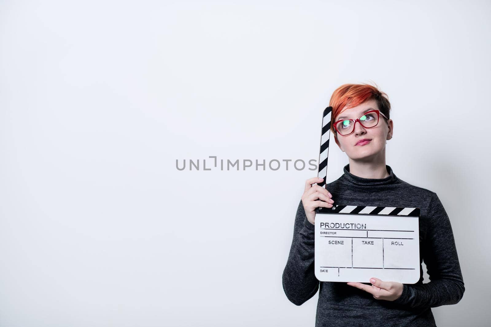 redhead woman on white background holding movie clapper cinema concept