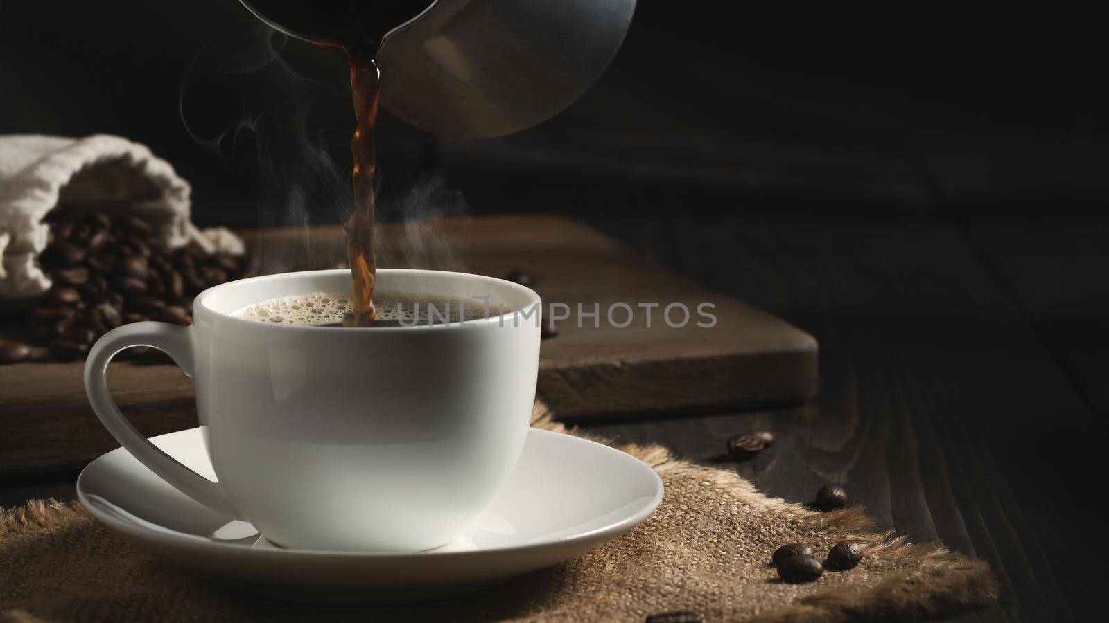 Pouring freshly brewed hot cezve coffee into a white cup.