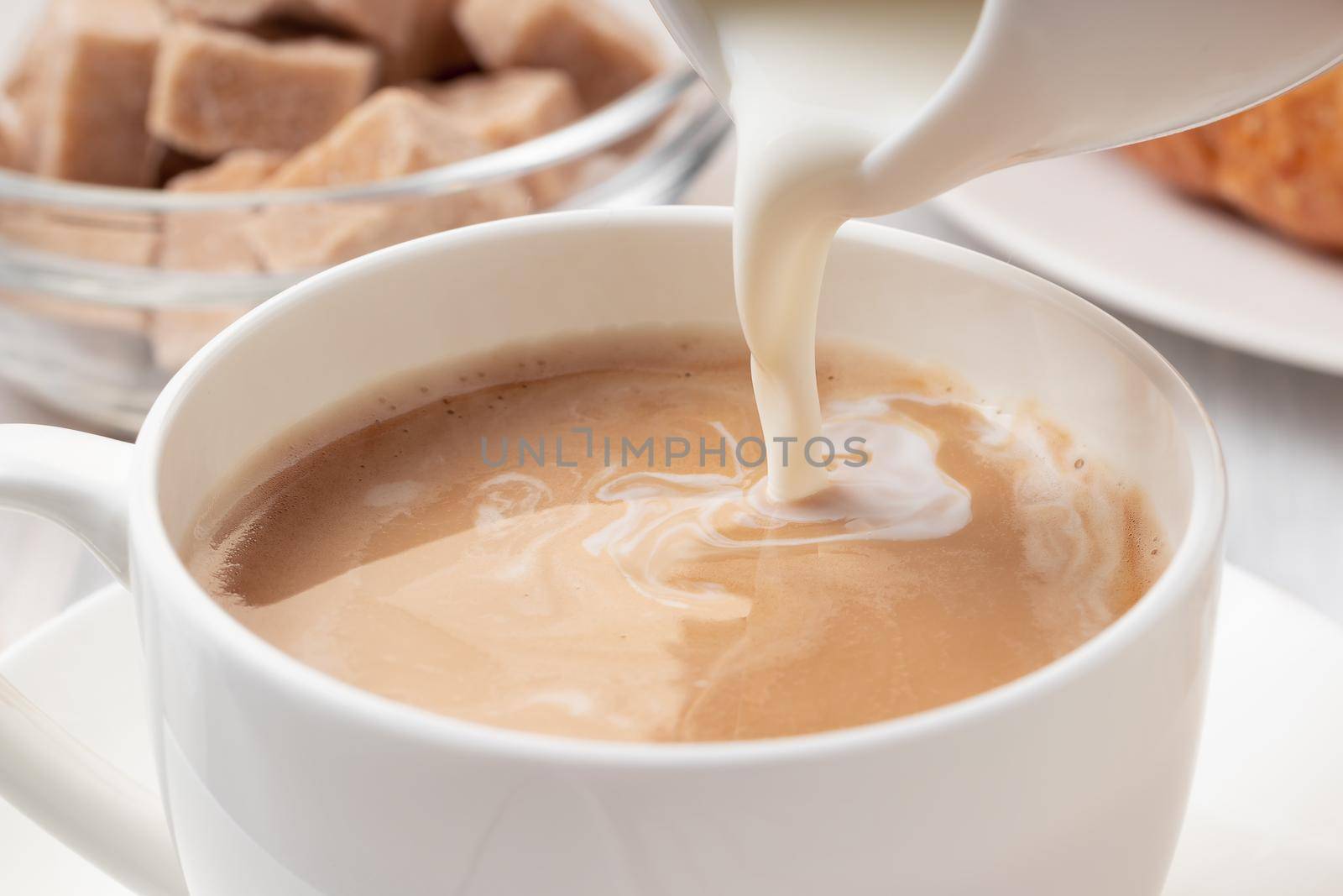 Pouring milk or cream into freshly brewed coffee, close up by galsand