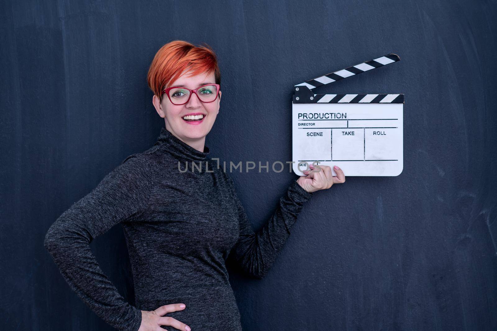 redhead woman on black chalkboard holding movie clapper cinema concept