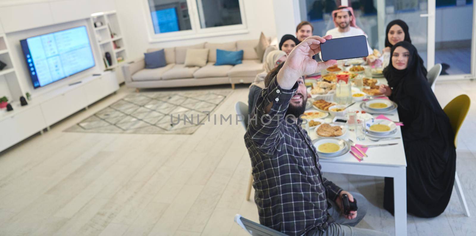 Muslim family taking selfie while having iftar together during Ramadan by dotshock