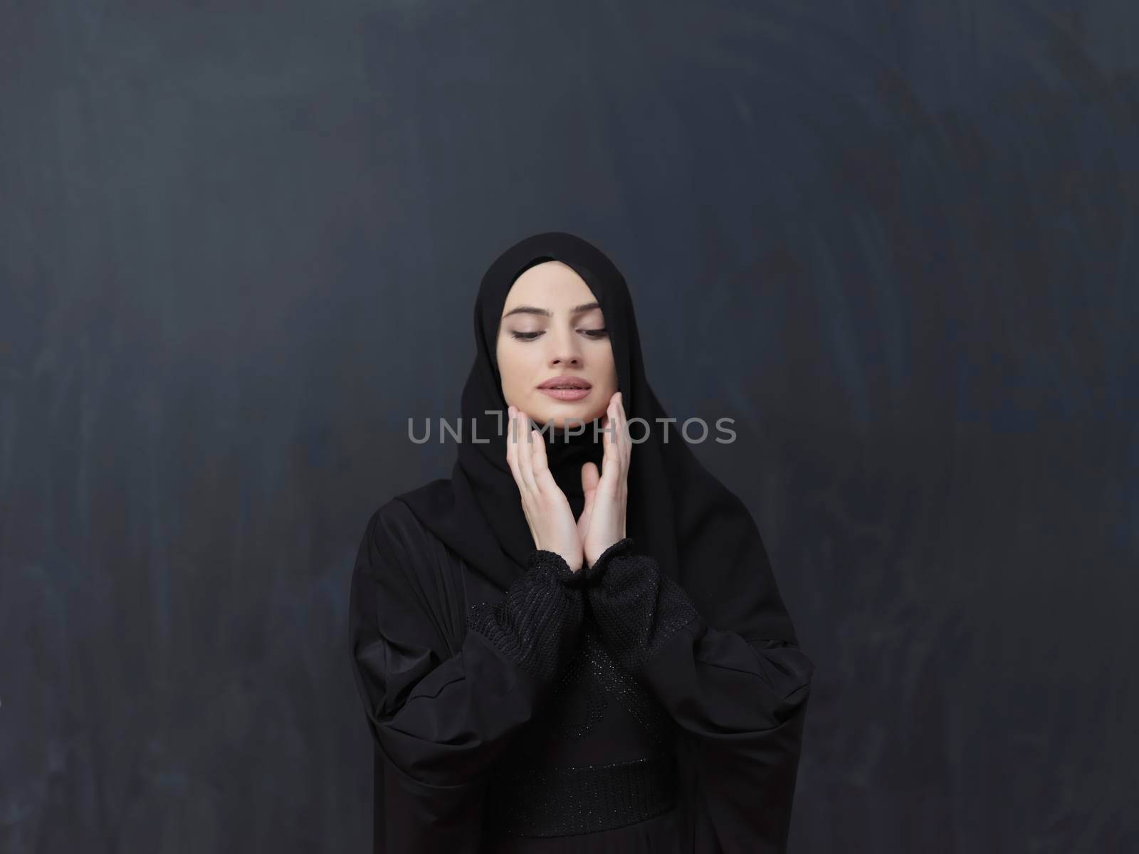 Portrait of young Muslim woman making dua. Arabian girl wearing abaya keeps hands in praying gesture. Representing worship to God and Ramadan Kareem concept