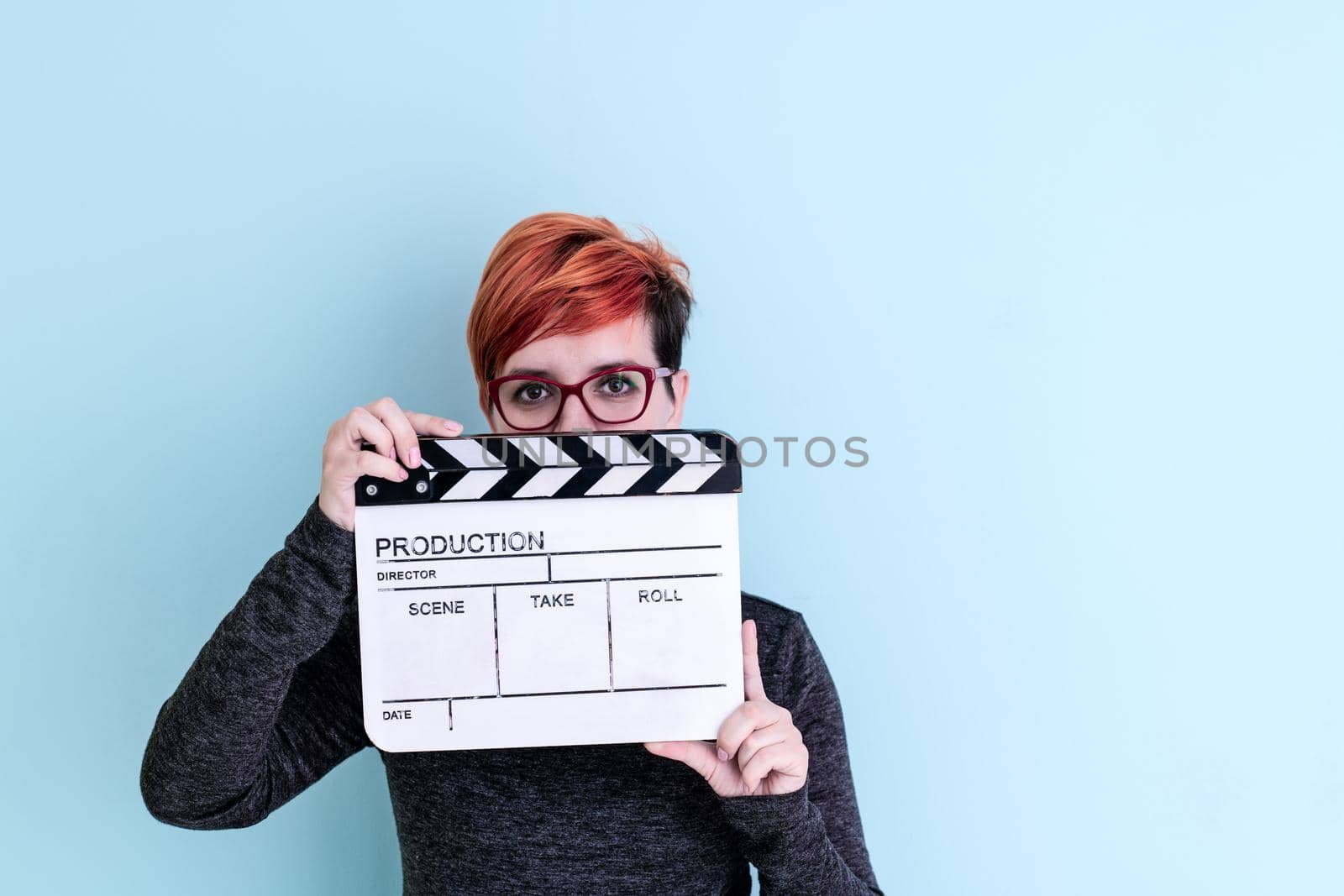 woman holding movie clapper against cyan background by dotshock
