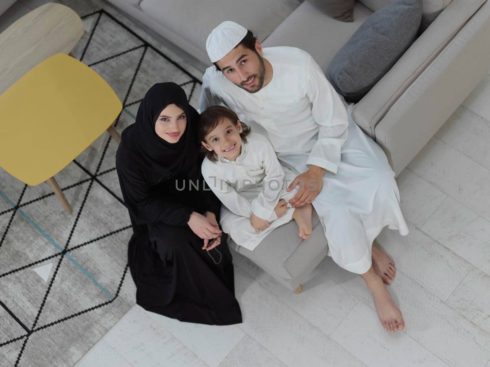 Top view of young arabian muslim family wearing traditional clothes at their modern house spending time together during Ramadan