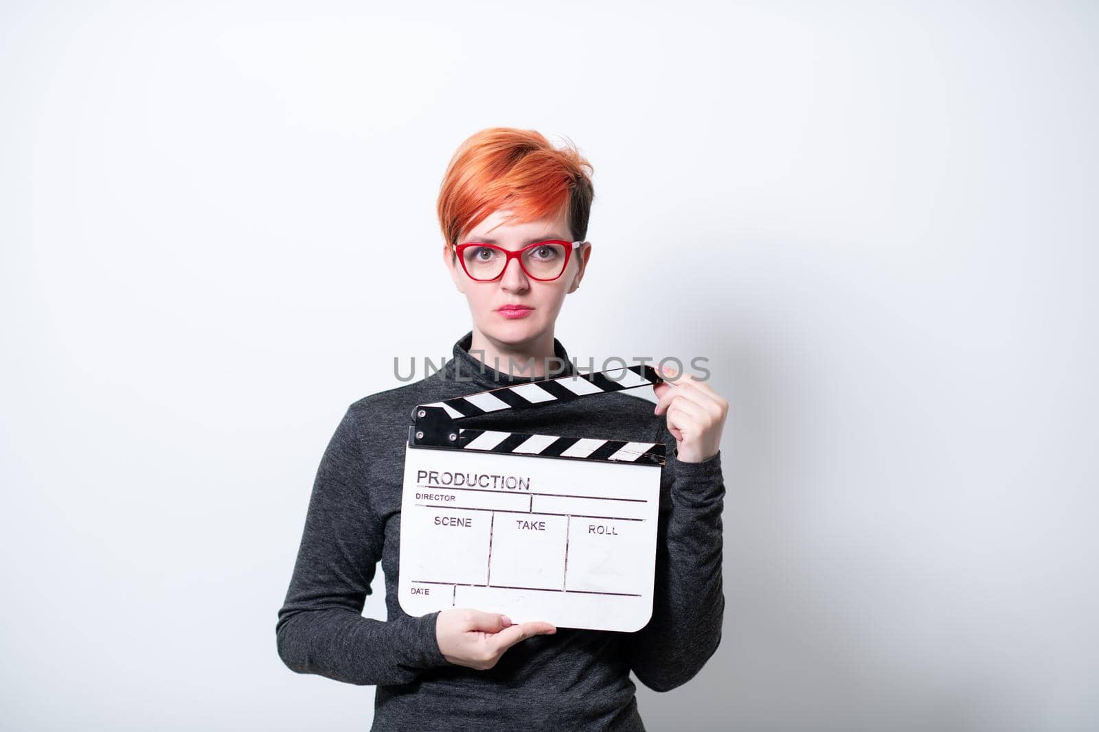 redhead woman on white background  holding movie clapper cinema concept