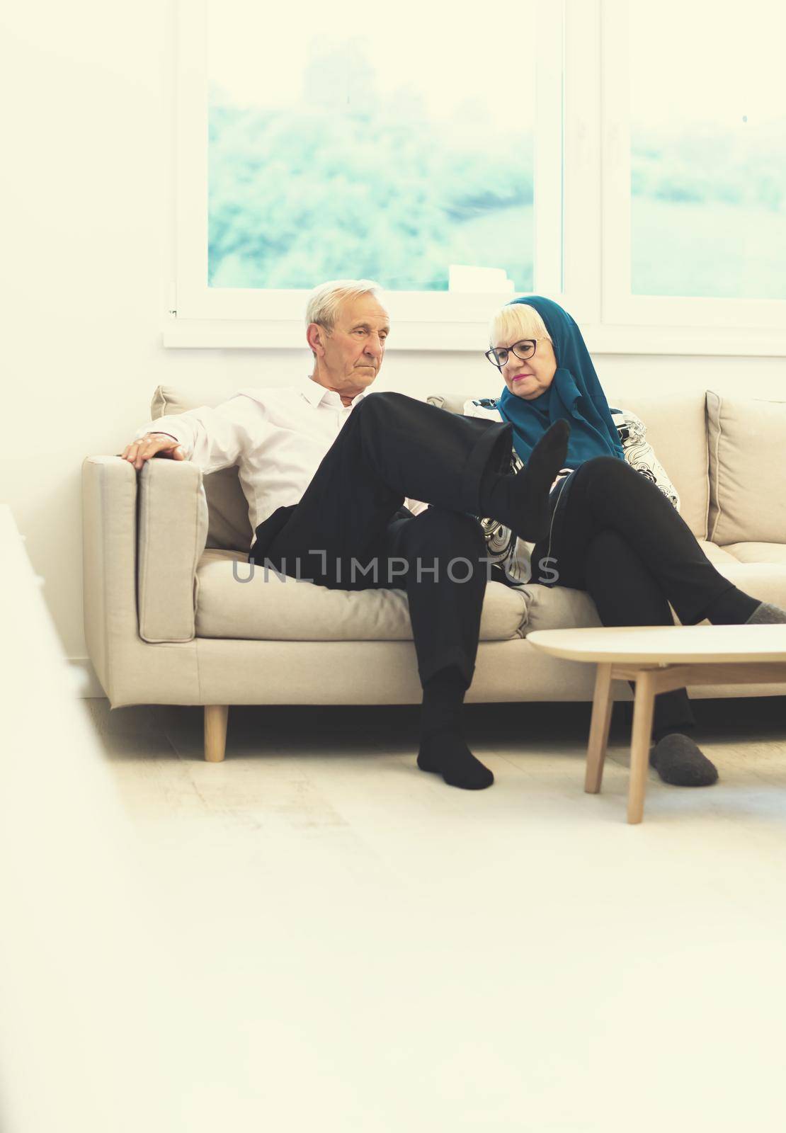 portrait of modern muslim senior couple sitting on the sofa before iftar dinner during a ramadan feast at home