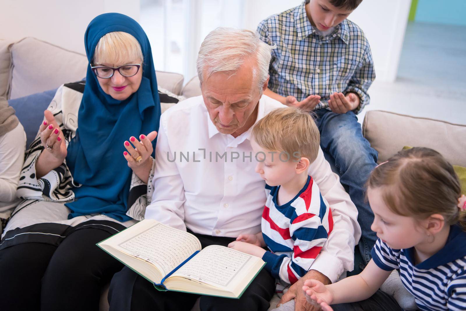 modern muslim grandparents with grandchildren reading Quran by dotshock