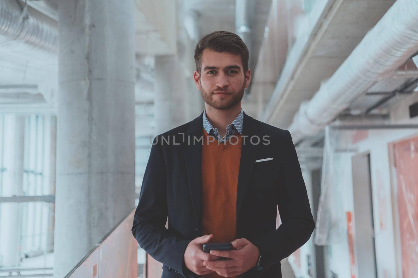 businessman architect expert using a smartphone while overseeing the construction site of a modern office building