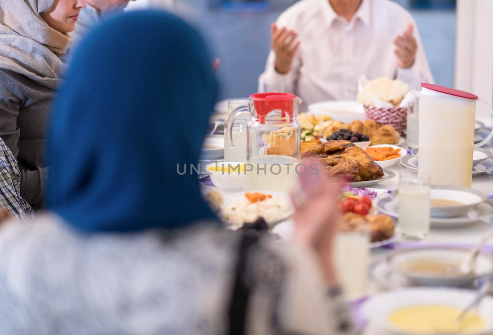 modern multiethnic muslim family praying before having iftar dinner by dotshock