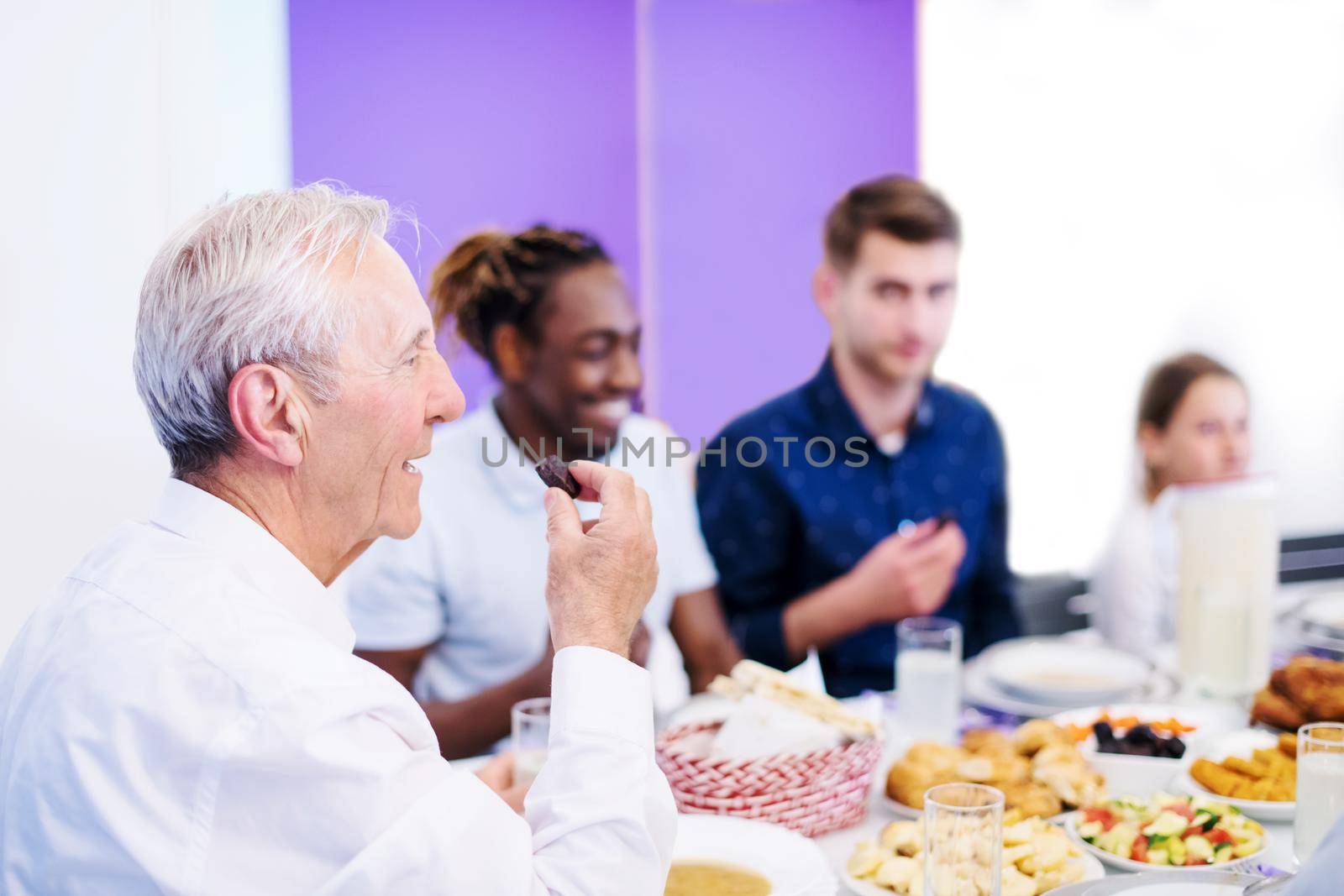 grandfather eating dates with modern multiethnic muslim family while enjoying iftar dinner together during a ramadan feast at home
