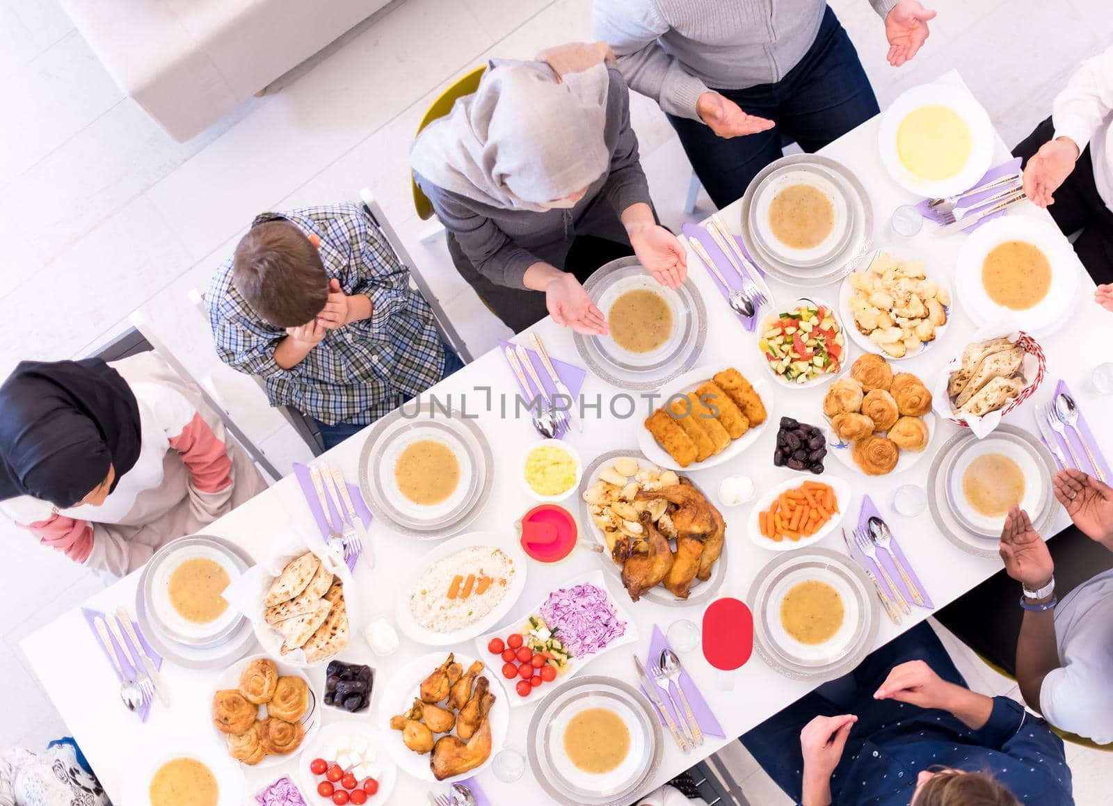 top view of modern multiethnic muslim family praying before having iftar dinner together during a ramadan feast at home