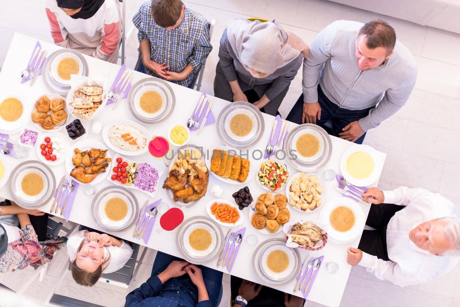 top view of modern multiethnic muslim family waiting for the beginning of iftar dinner during a ramadan feast at home