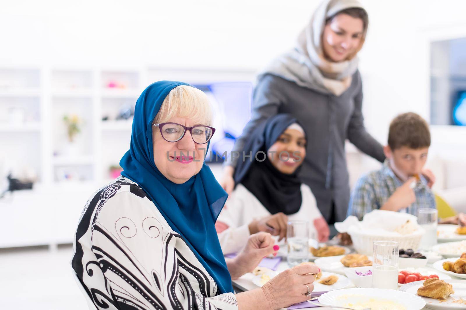 modern muslim grandmother enjoying iftar dinner together with multiethnic family during a ramadan feast at home