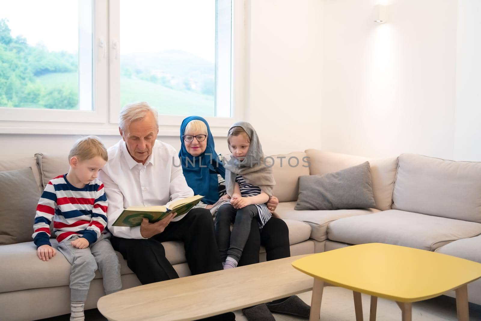 modern muslim grandparents with grandchildren reading Quran by dotshock