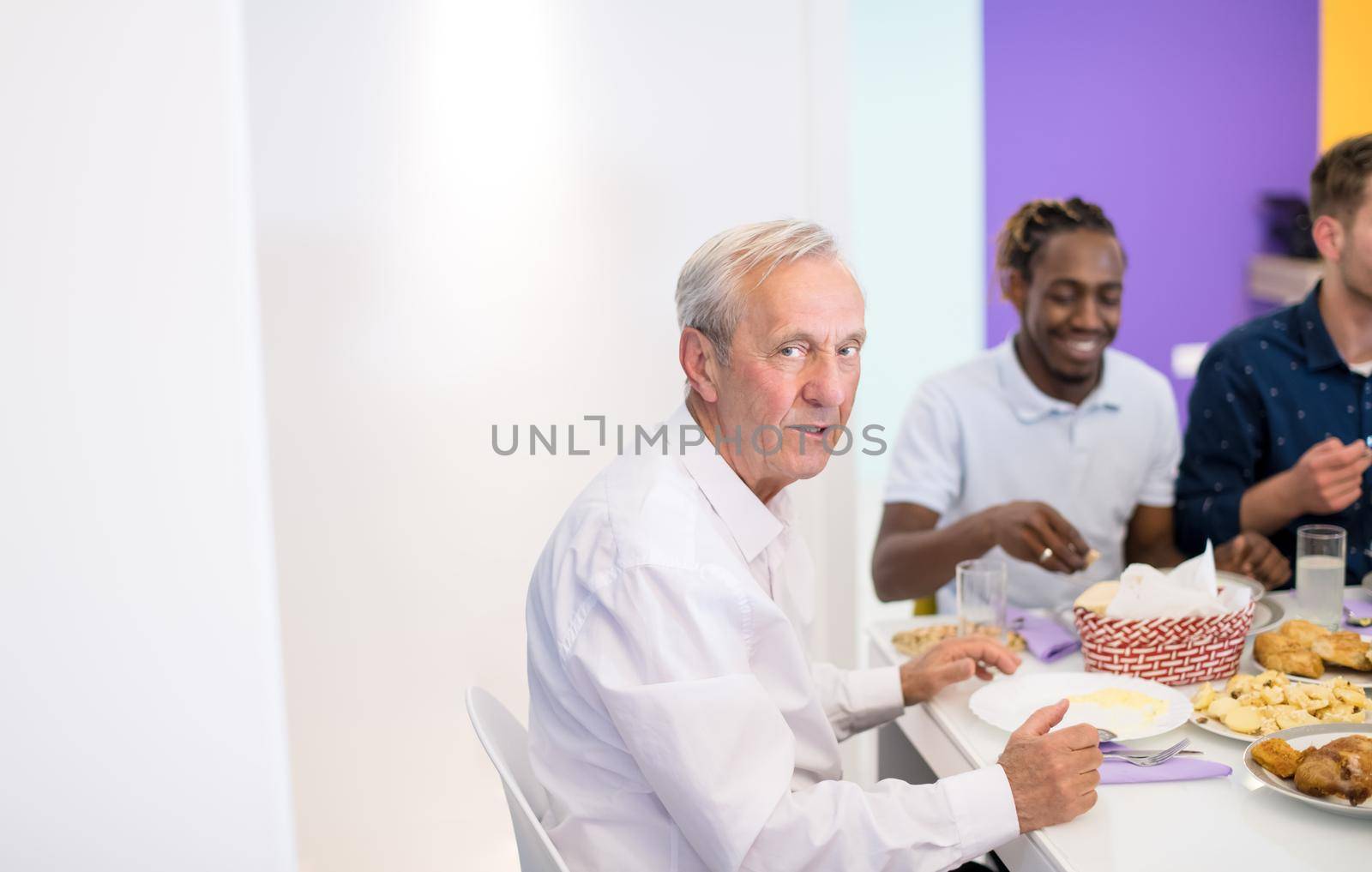 modern muslim grandfather enjoying iftar dinner together with multiethnic family during a ramadan feast at home