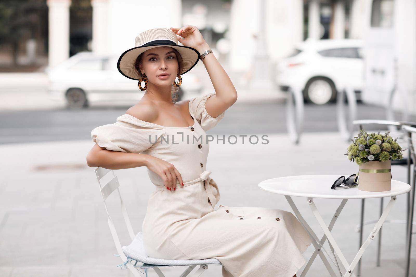 Fashion young woman in sunglasses with hat in street cafe with coffee. High quality photo