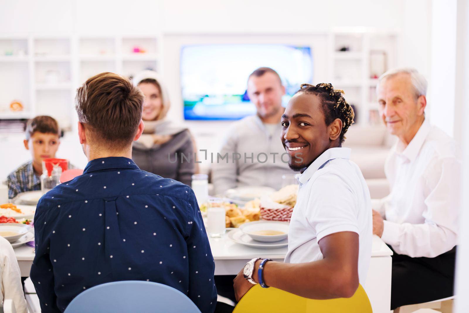 african american man enjoying iftar dinner together with modern multiethnic muslim family during a ramadan feast at home