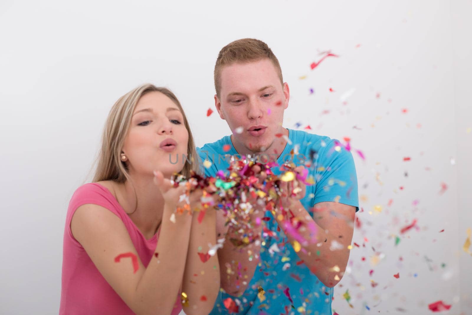 happy young romantic  couple in love  celebrating and blowing confetti decorations at new year and charismas  party