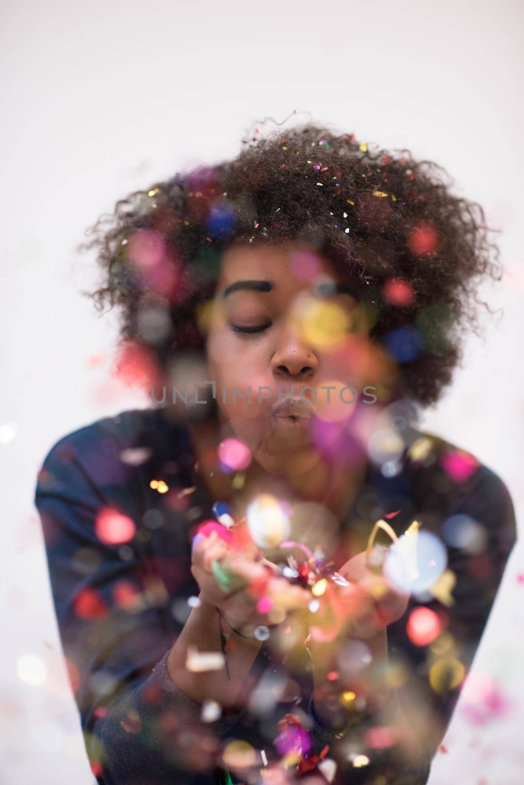 happy young woman celebrating new years eve party while blowing confetti