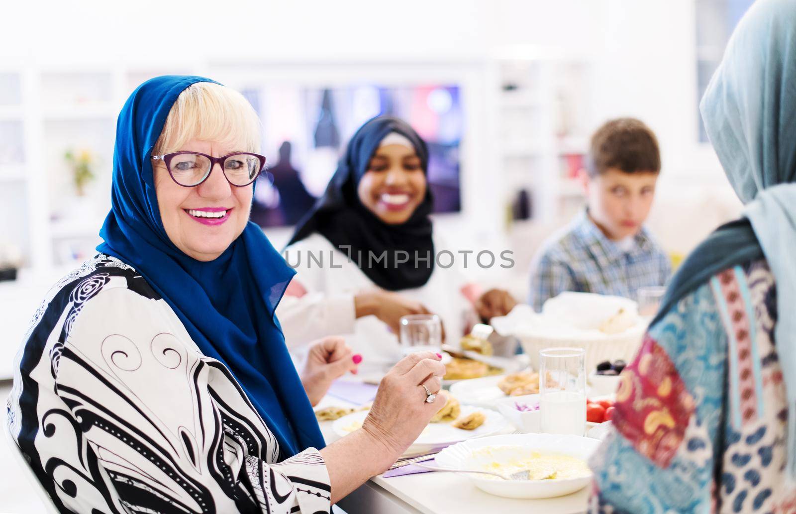 modern muslim grandmother enjoying iftar dinner together with multiethnic family during a ramadan feast at home