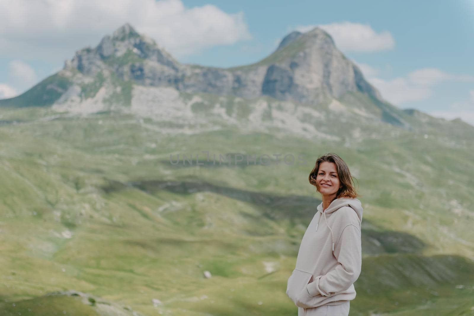 Hiker tourist girl standing on top of the mountain and enjoying valley view. Happy woman with her arms outstretched, freedom and happiness, achievement in mountains.