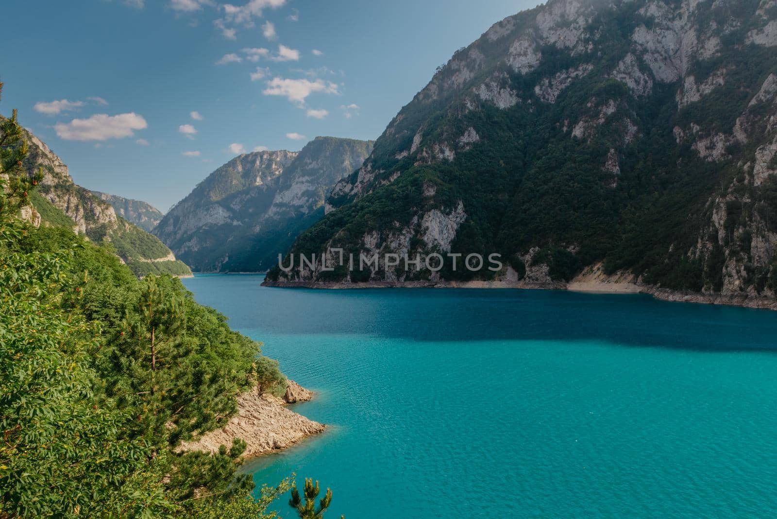 The concept of eco-tourism and active recreation. National Park. Mountain Emerald lake in the wooded mountains. Sunny day in autumn.