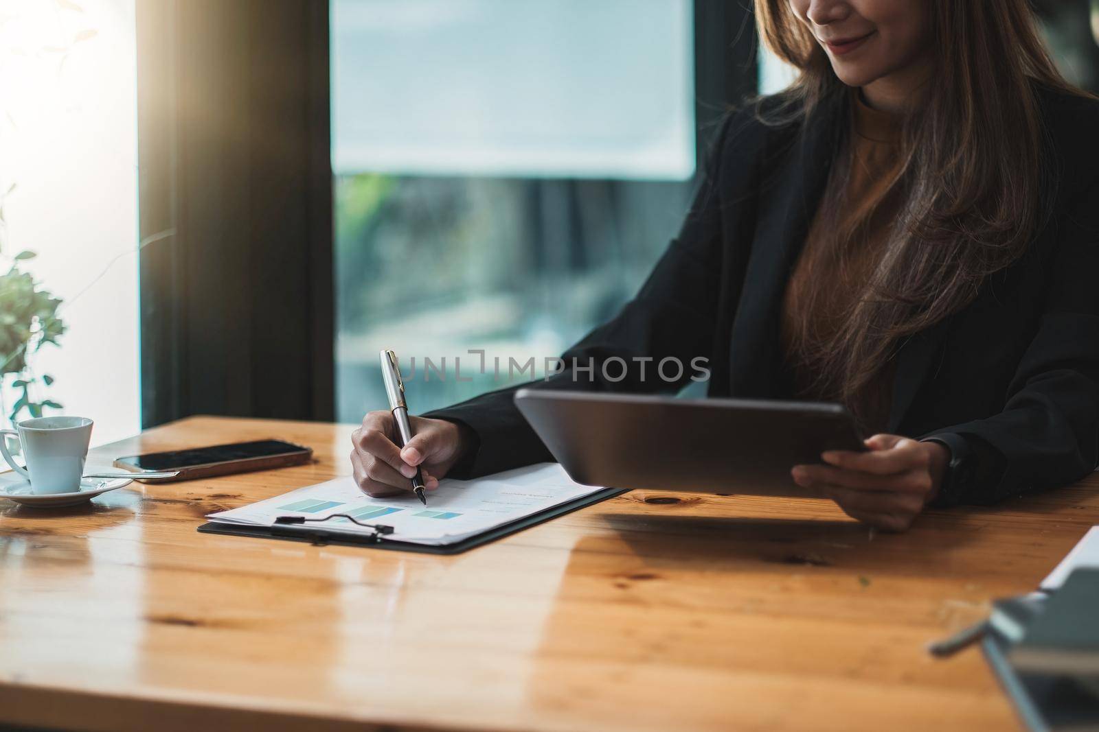 Asian businesswoman investment consultant analyzing company annual financial report balance sheet statement working with digital tablet. Concept picture of business, market, office, tax.