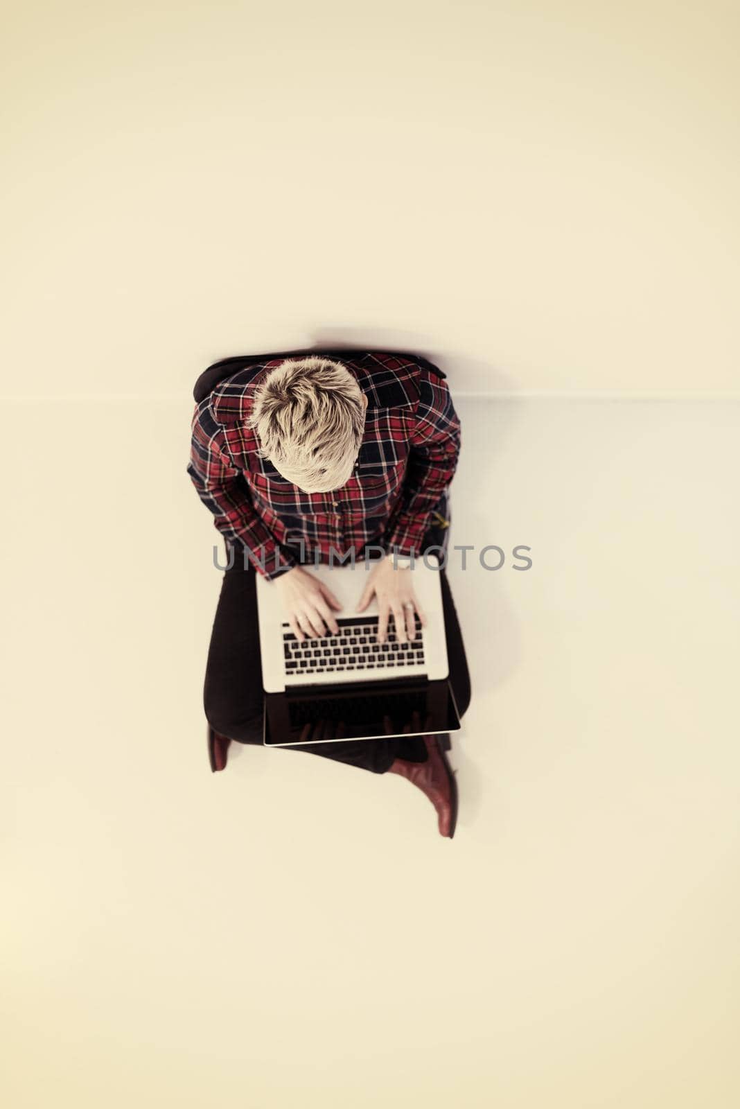 top view of young business woman working on laptop computer in modern bright startup office interior, sitting on floor