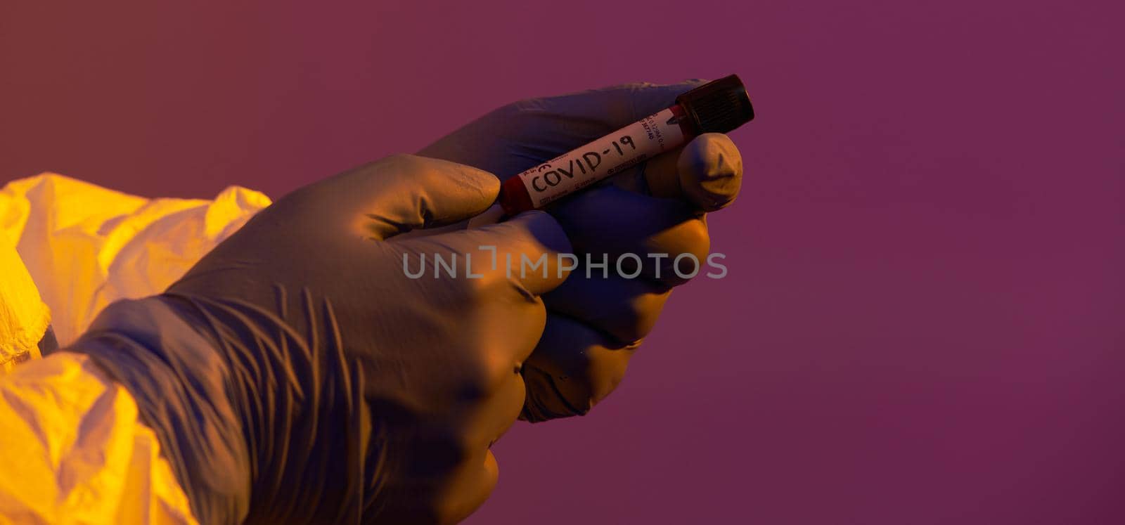 Coronavirus, Doctor holding positive covid-19 virus Blood Sample test tube. Wearing biohazard epidemic Protective mask, suit and glows neon light background