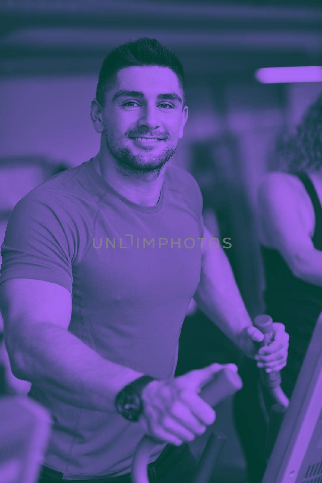 Handsome man running on the treadmill in modern gym duo tone