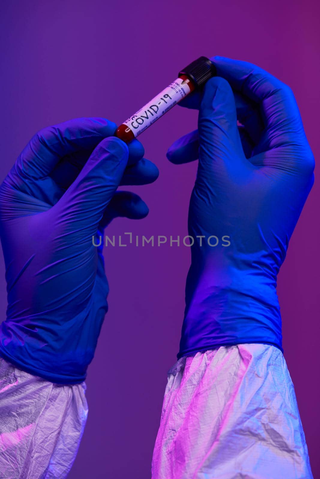 Coronavirus, Doctor holding positive covid-19 virus Blood Sample test tube. Wearing biohazard epidemic Protective mask, suit and glows neon light background