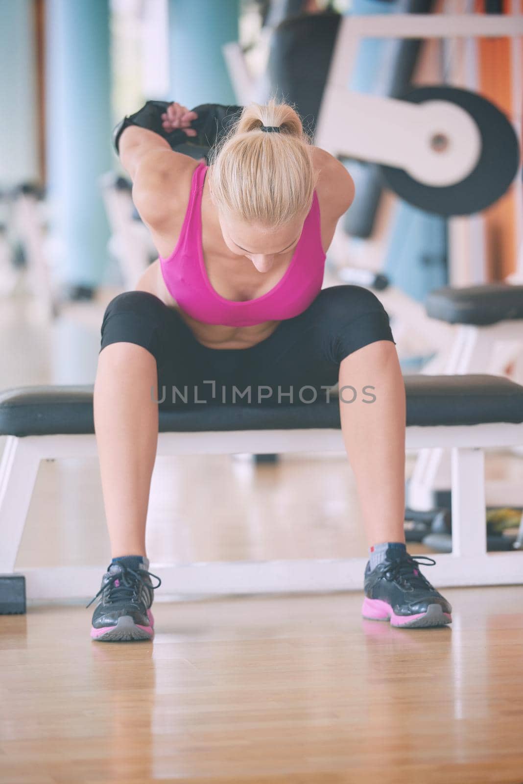 Cute young woman stretching and warming up for her training at a gym