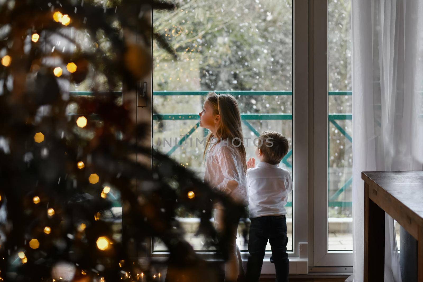 Children look at the snow through the window Christmas