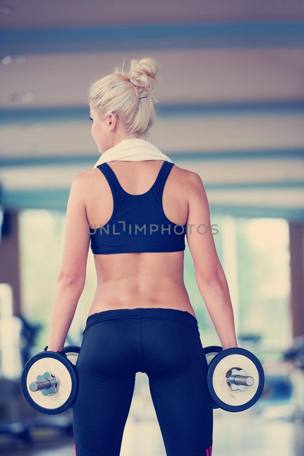 Gorgeou woman girl lifting some weights and working on her biceps in a gym