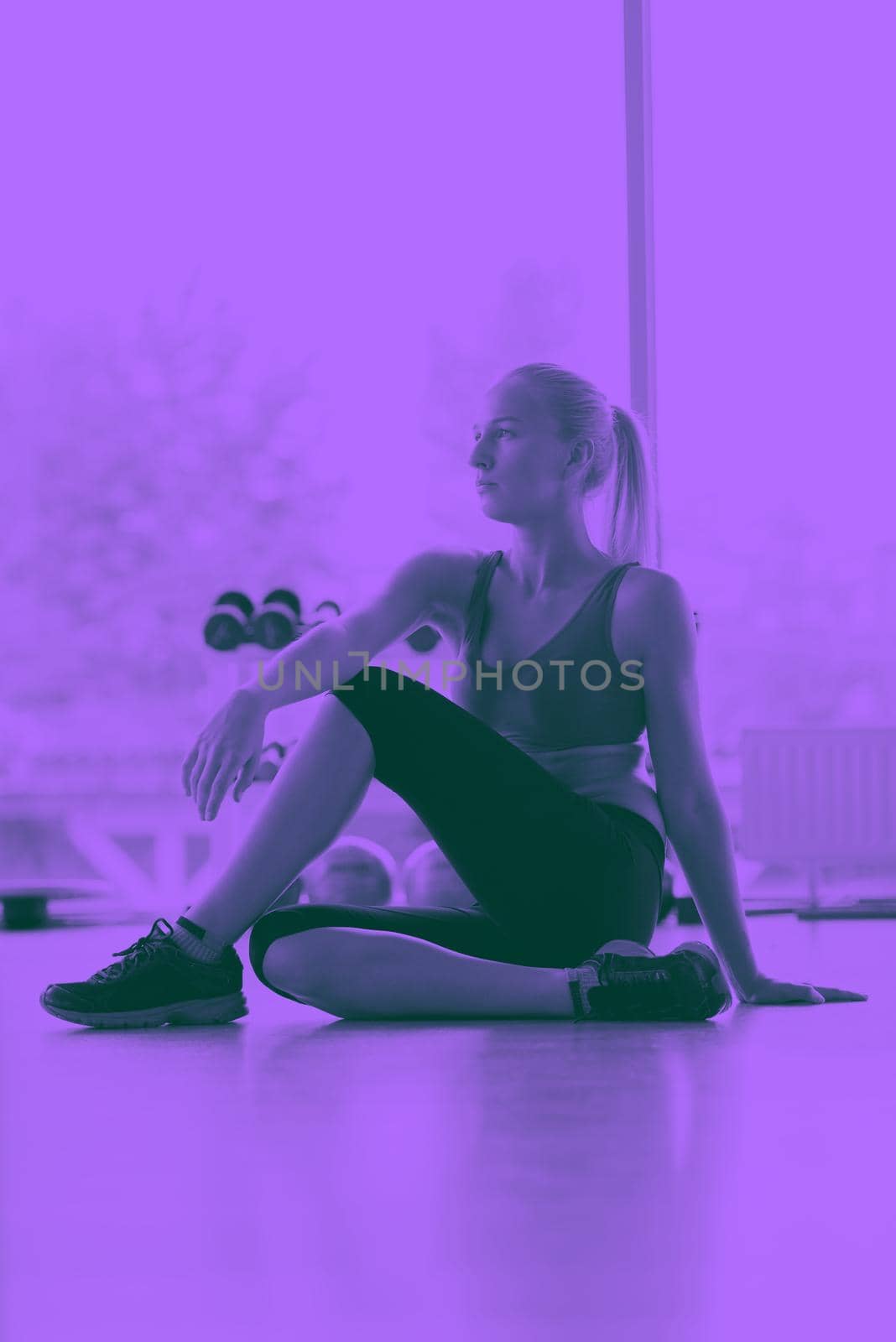 Cute young woman stretching and warming up for her training at a gym duo tone