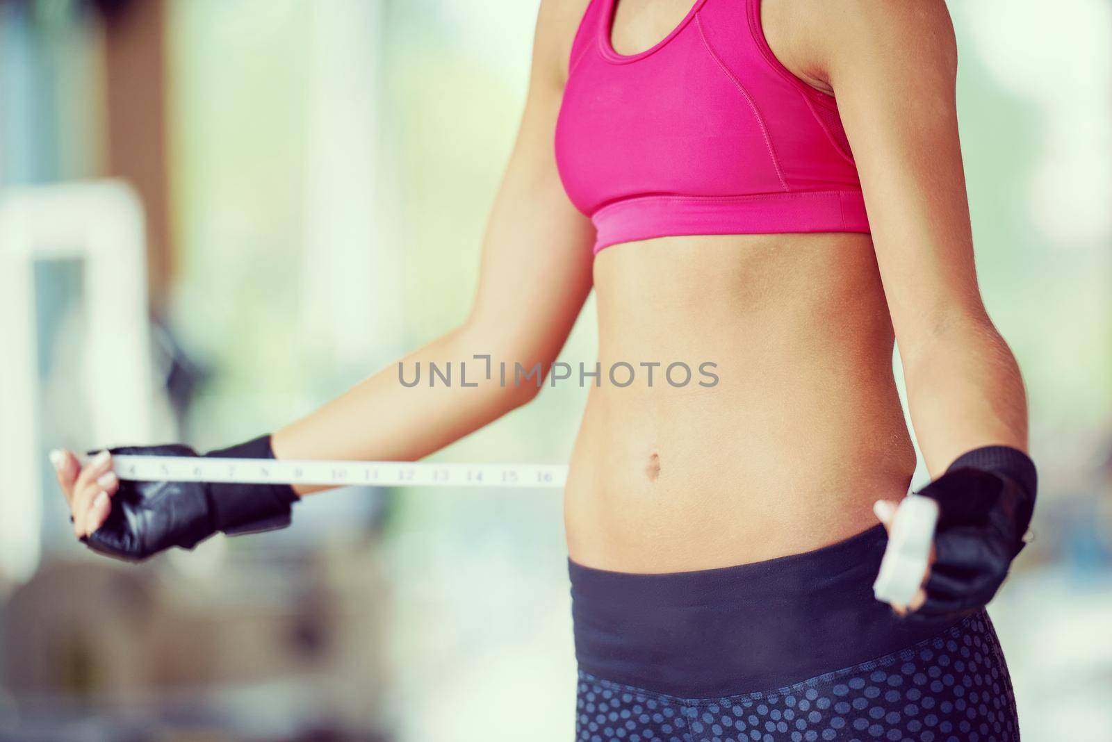 young fit woman measuring belly by dotshock