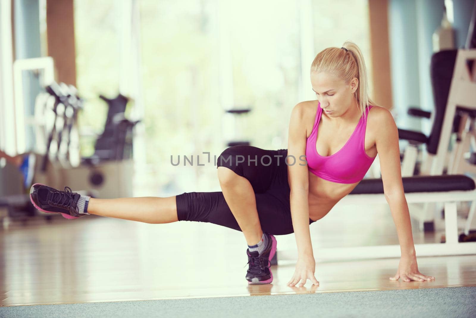 Cute young woman stretching and warming up for her training at a gym